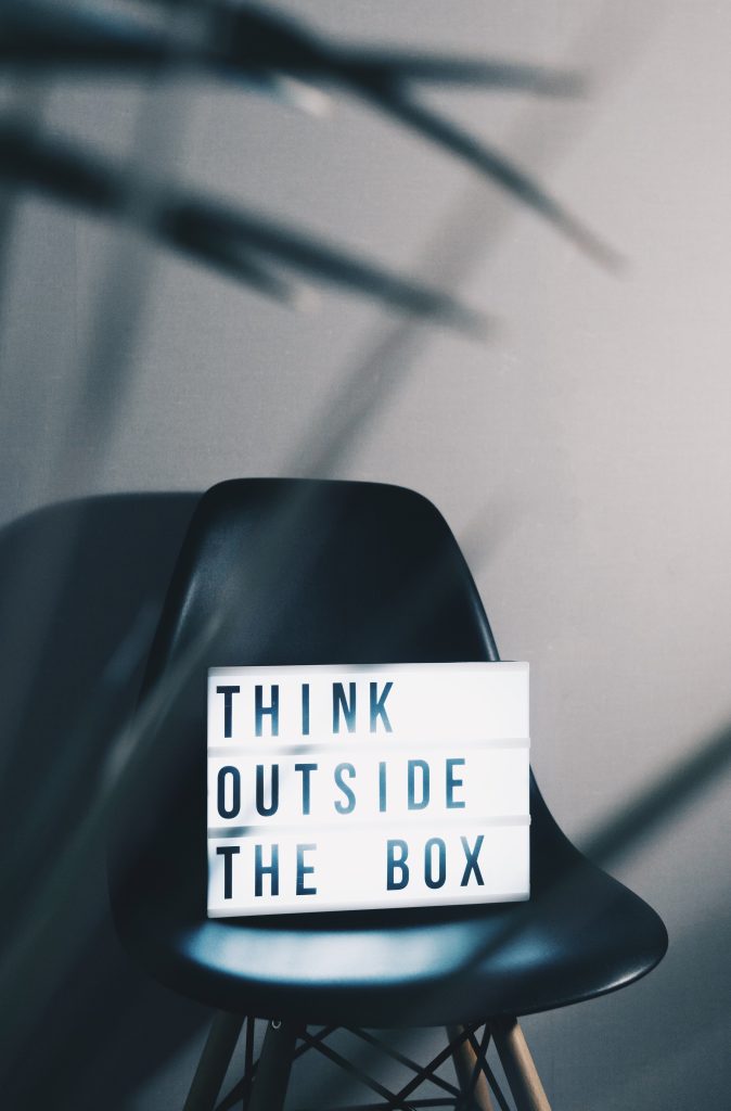 A lightbox with the words "think outside the box" on a chair in front of a wall