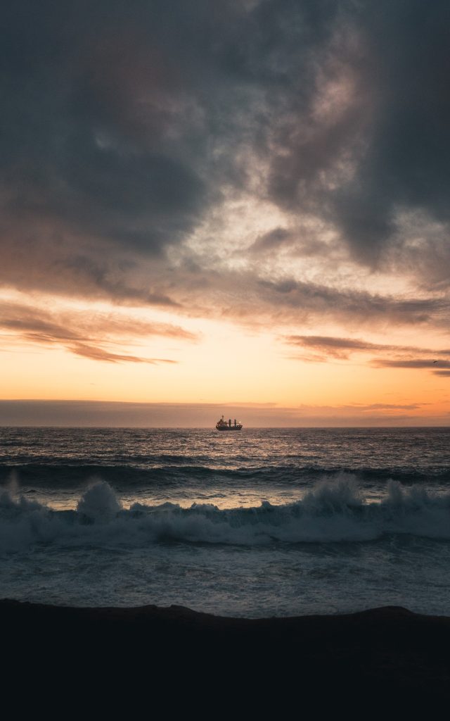 A photograph of the sea with waves and a ship in the distance