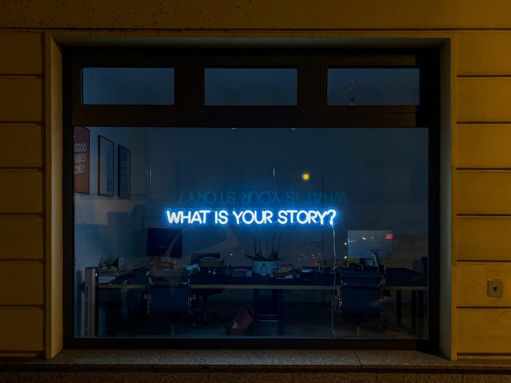 A dark window with illuminated text in capitals which reads 'What is your story?'
